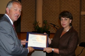 Rear Adm. Willem Voogt, RNLN (Ret.), chapter president, presents a certificate of appreciation to Elly van den Heuvel, general manager of GOVCERT.NL, the Dutch government's computer emergency response team. Van den Heuvel served as a keynote speaker during the August meeting.